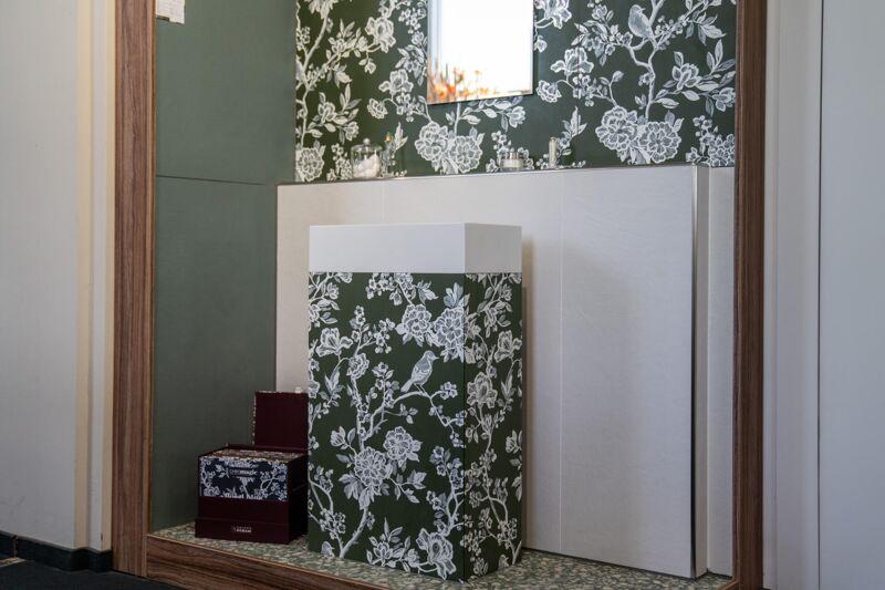 Waschtischsäule und Wand mit grün-weißem Blumendekor in einer Bad-Koje der Ausstellung Bonn